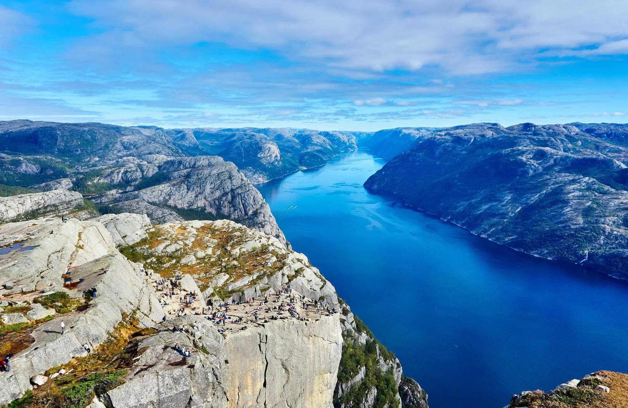 A deep blue fjord between grey cliffs, seen from above